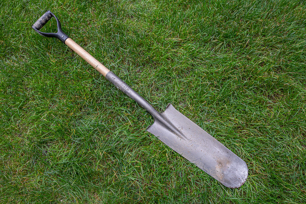 Trenching shovel with d grip handle laying on ground